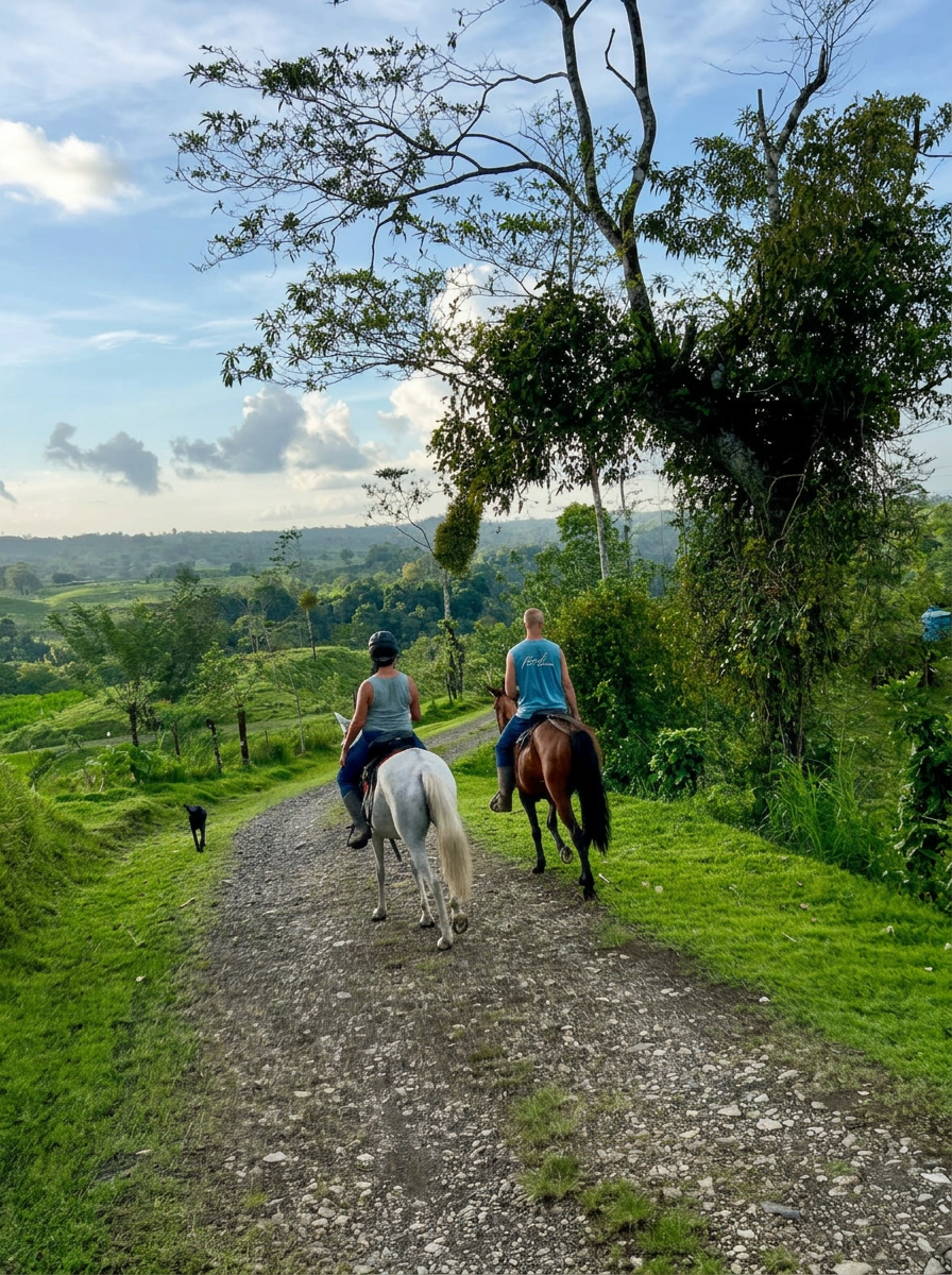Two riders heading out on horseback along the ranch trail with the valley beyond